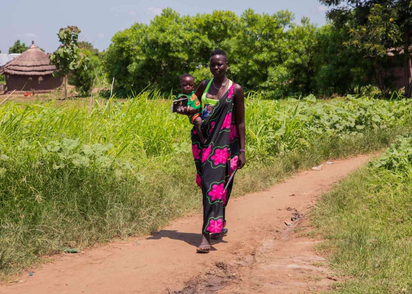 A mother carries her child along the roadside on the way to seek care, South Sudan