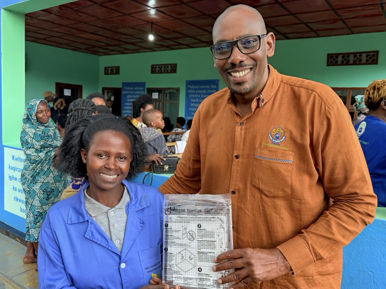 Executive Director Manasseh Gihana with a community health worker, holding an SC Johnson Guardian spatial repellent